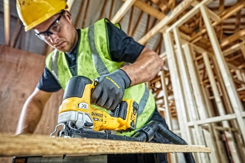 Scie sauteuse DEWALT DCS334P2 utilisée pour couper du bois sur chantier par un ouvrier équipé.